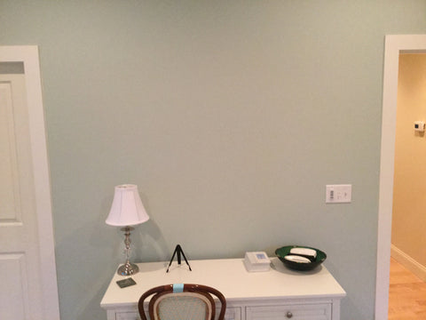 a light blue blank wall between two doors, with a small white desk underneath
