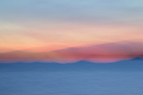 Abstract landscape photo of a lake scene with cobalt blue in the bottom third and red and orange undulations on the horizon and blue sky above