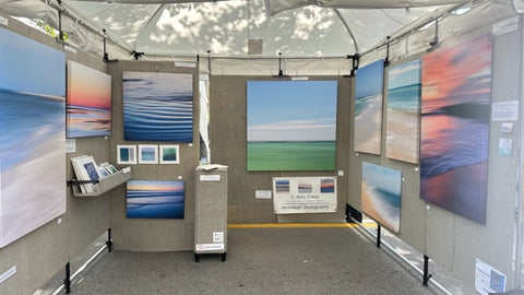 art booth with grey walls with sunset snd tropical abstract landscape photos in bright colors