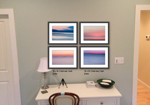 A small blue wall with a white desk underneath, between two doors.  There are four photos superimposed on the wall, all sunsets, showing the theoretical placement of the artwork 