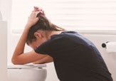 Woman vomiting in toilet