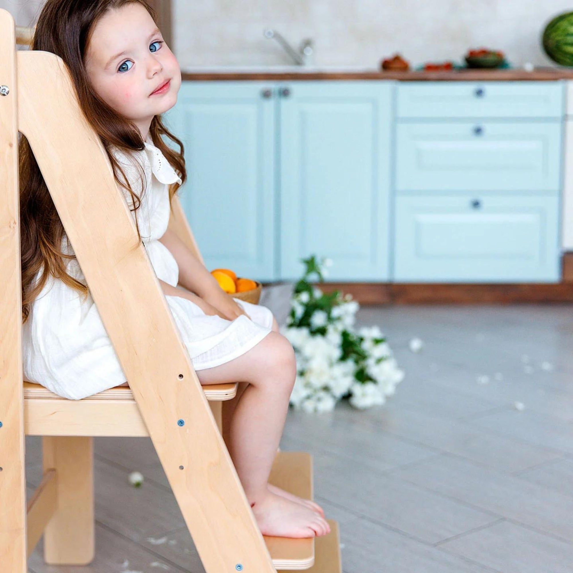 Kleines Mädchen sitzt auf der Plattform des Lernturmes.