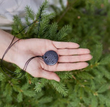 Shungite pendant being held in the palm of a person. 