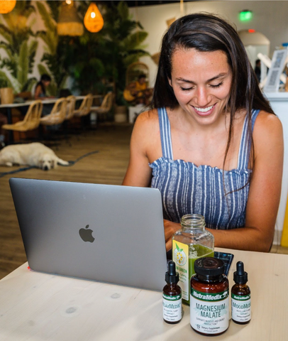 Girl working on laptop with health supplement kit next to her