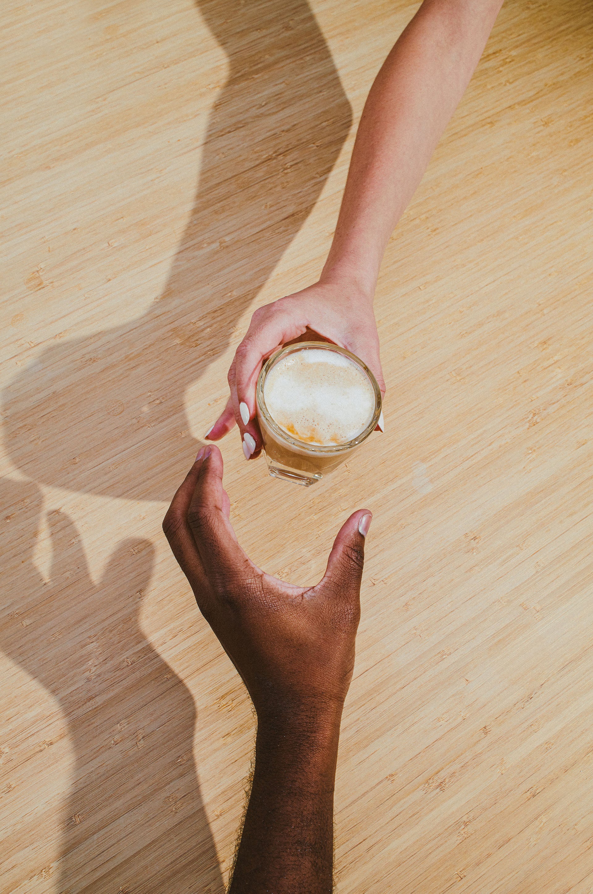 Person passing a coffee beverage from one person to the other