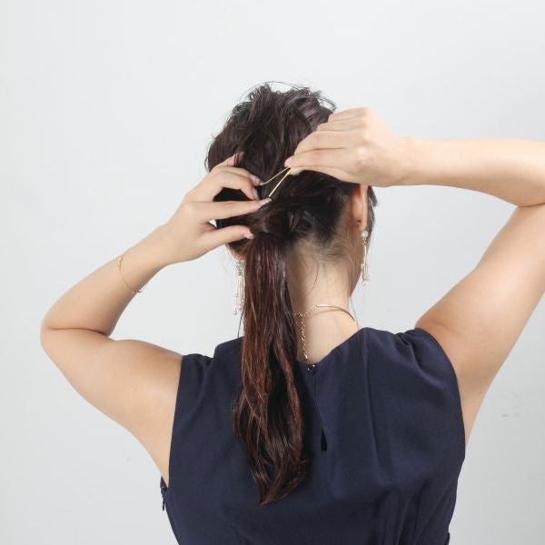 ねじった髪の毛を、一つ結びのゴムが隠れるように巻きつけ、毛先が隠れるようにピンで留めれば完成。