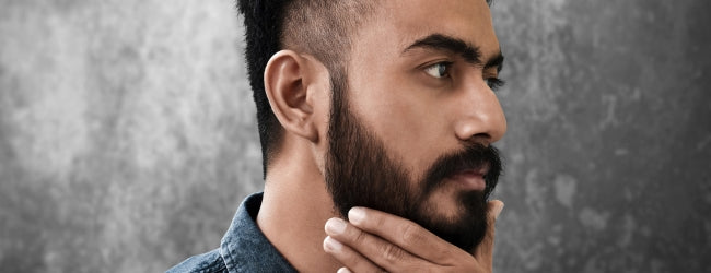 Bearded man looking into the distance and stroking beard