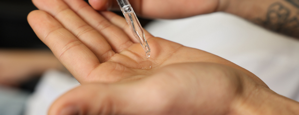 Man using a dropper top to dispense beard oil to hand