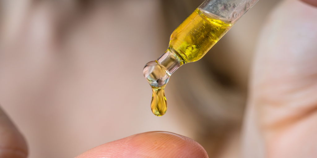 Yellow beard oil being dispensed into hand