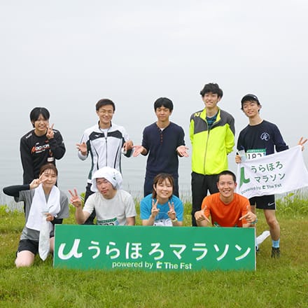 「うらほろマラソン」と書かれた看板にあつまって記念撮影をする参加者たち