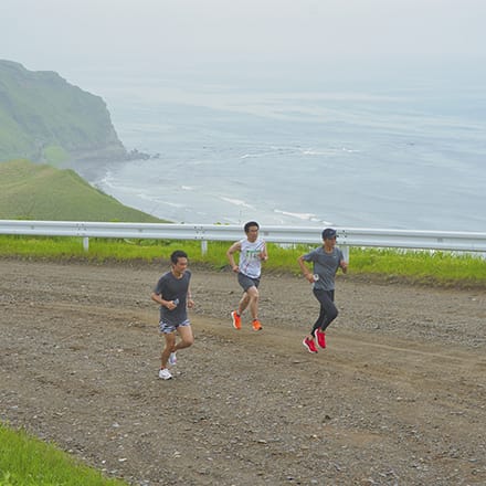 コースを走る3名の参加者、奥に海が見える