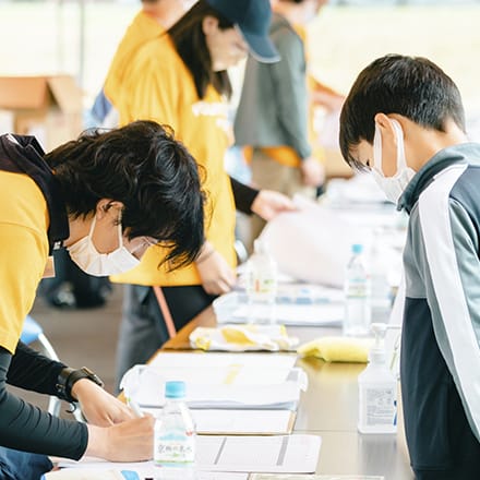 受付をするボランティアとそれを見つめる子供の来場者