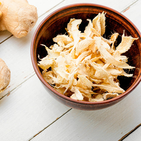 dried ginger, in bowl on white wooden table.