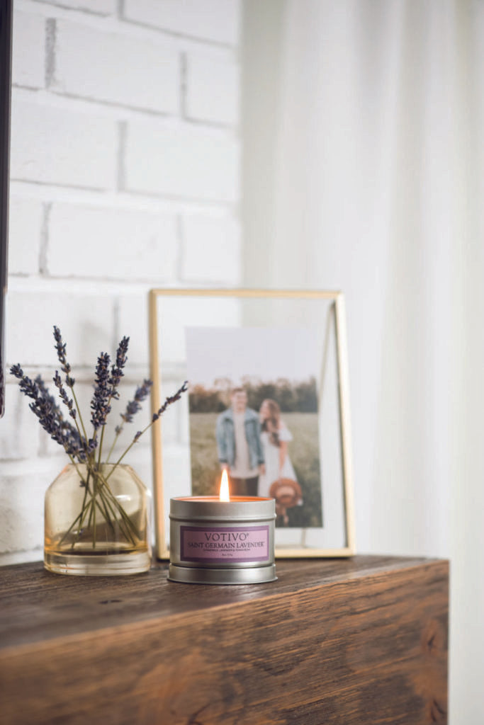 a candle near a photo frame and a vase with herbal flowers