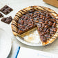 pecan pie with chocolate drizzle, slice taken out with decorative chocolate in the photo
