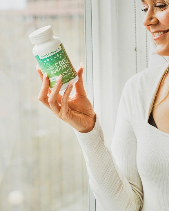 woman smiling holding bottle of full-spectrum CBD gummies