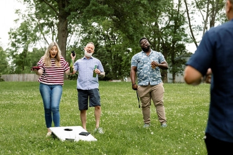 friends-playing-cornhole-summer-party-park