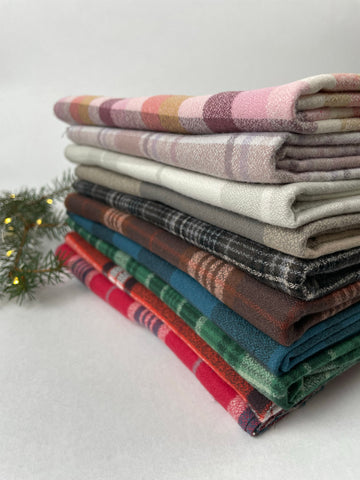 Pile of organic cotton plaid flannel pieces in a variety of plaid colors.