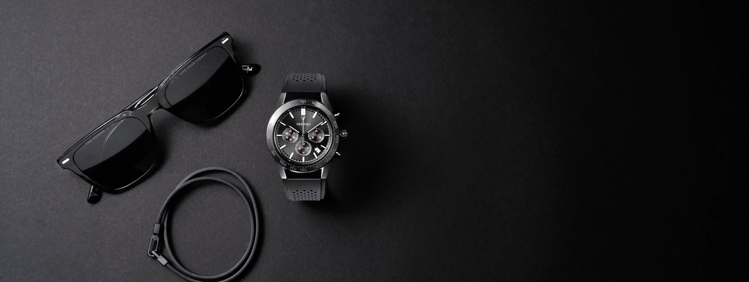 Black sunglasses, watch, and bracelet in matte black background