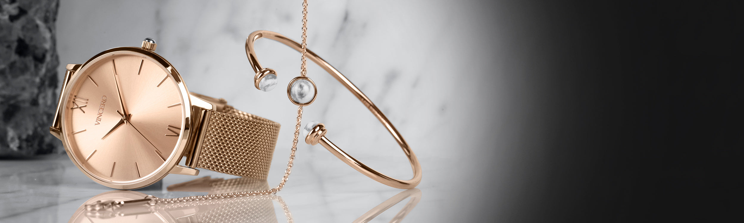 Rose gold watch with mesh strap with rose gold bracelet and cuff in white marble background