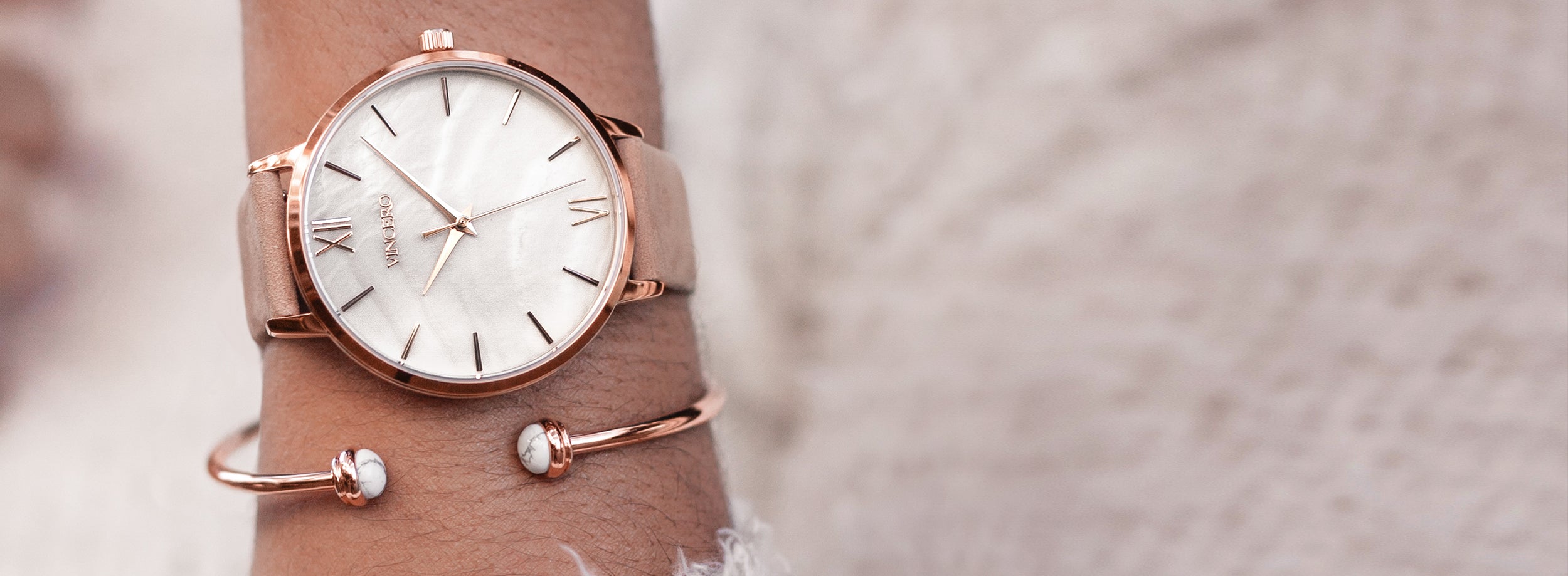 Close up white marble and rose gold watch with rose gold cuff bracelet