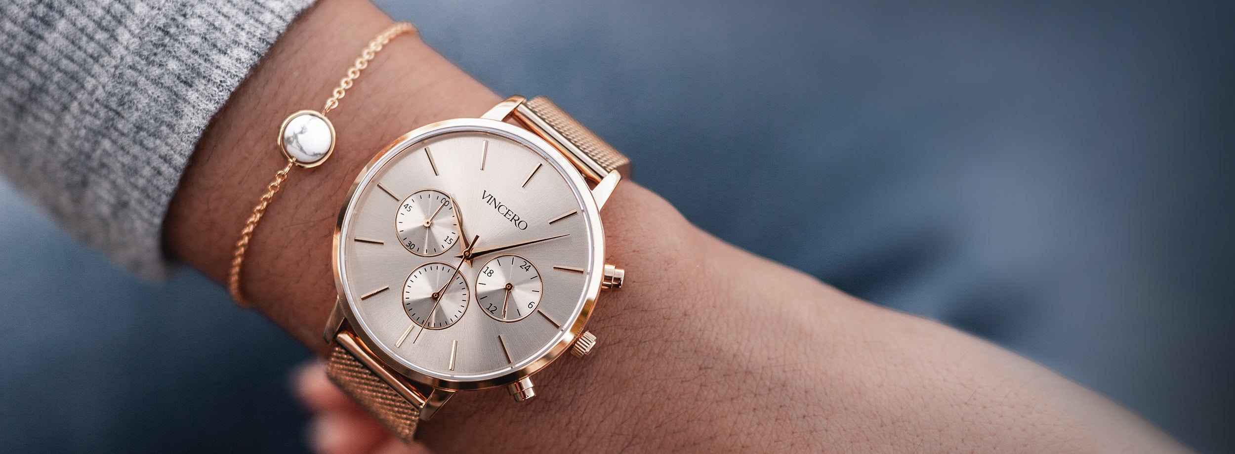 Close up white and gold watch with gold mesh strap with rose gold bracelet