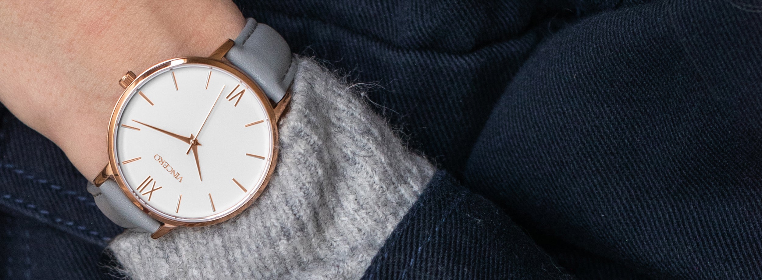 Close up of white and rose gold watch with grey leather strap