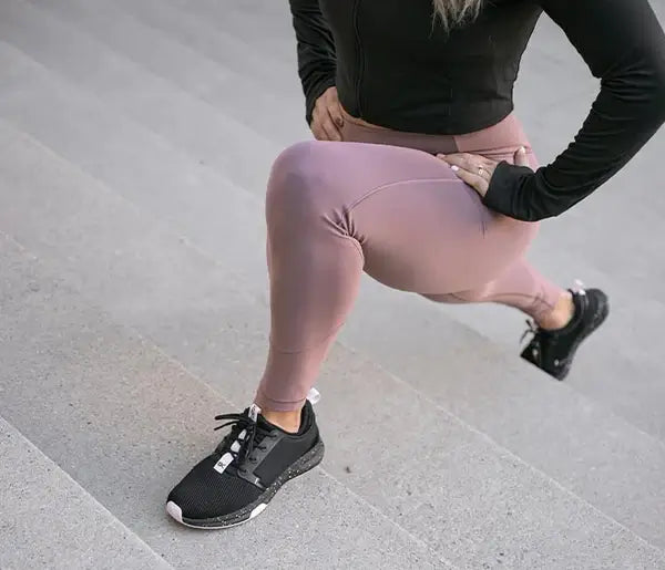 A woman wearing KURU ATOM athletic sneakers stretching on a flight of steps