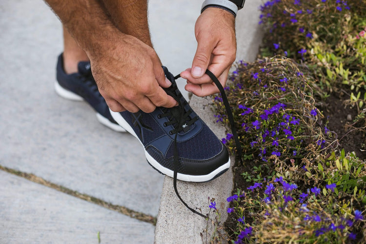 Man tying the shoes of his KURU QUANTUM corrective shoes.