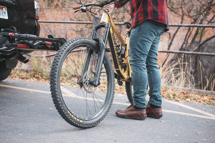 A man wearing KURU QUEST shoes for mountain biking preps his mountain bike for the trail.