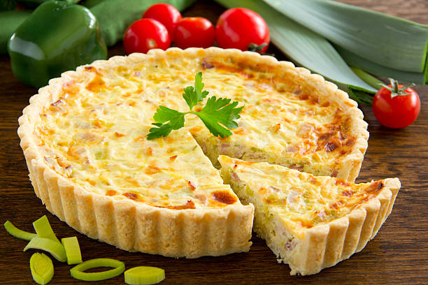 Une quiche avec des poireaux, des tomates et des poivrons sur une table