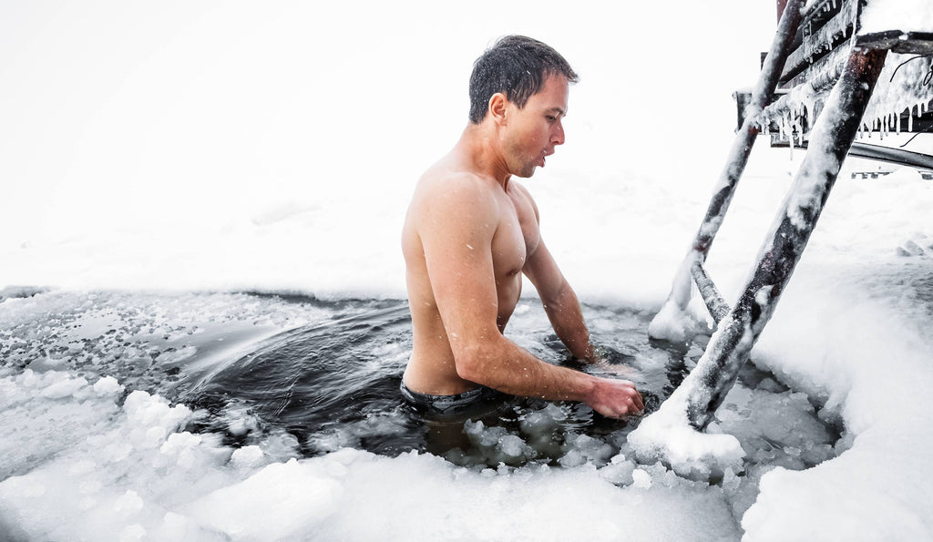 Young man cold plunging in a frozen lake