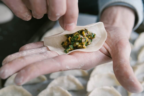 Raw pork dumplings with Chinese chives being folded. Photo by Matthieu Joannon.