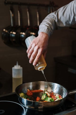 Adding oil to a stainless steel skillet for easy food release.