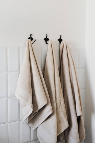 Set of cotton towels hanging on towel hooks. Photo by Karolina Grabowska.