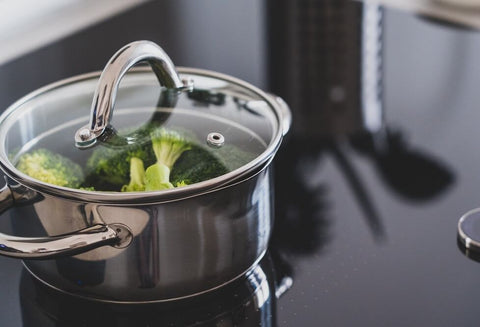 Stainless steel pot with a glass lid on an induction cooktop.