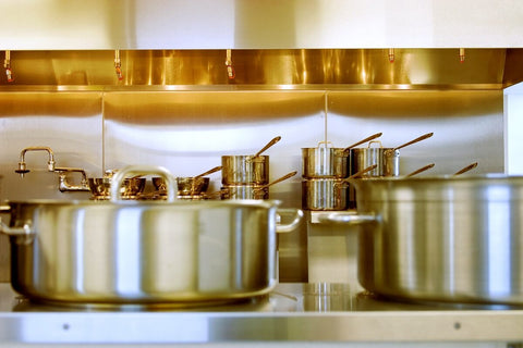 Stainless steel cookware in a commercial kitchen. Photo by Adam Dachis on Unsplash.