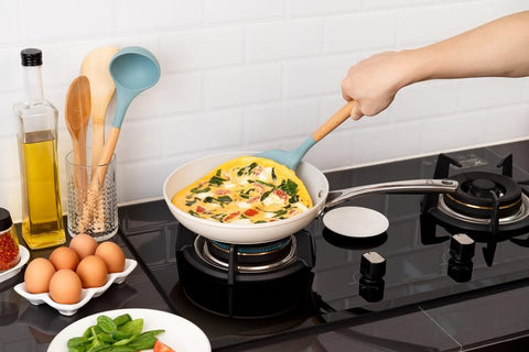 Cooking frittata with a silicone spatula on a nonstick pan.