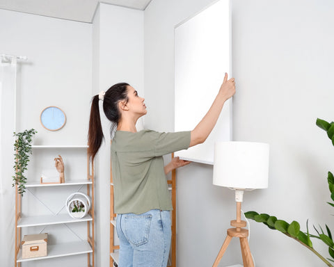 A women installing the infrared heating panel on wall