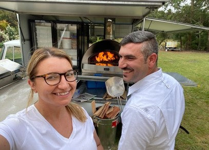 Gianna and Vincenzo standing in front of their pizza oven