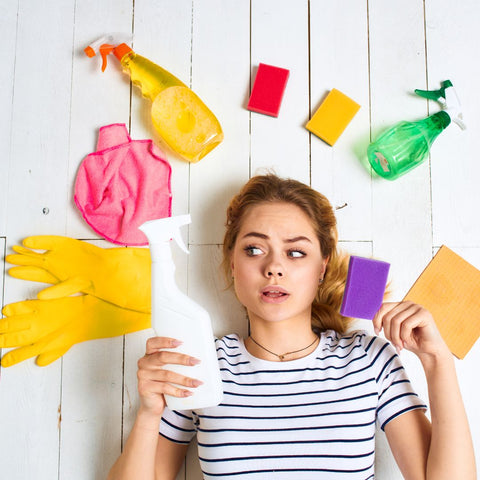 Confused looking college student with lots of cleaning products around her