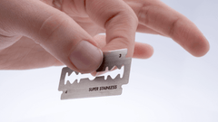 image of a hand carefully holding a safety razor blade