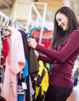 a woman shopping for clothing in a thrift store