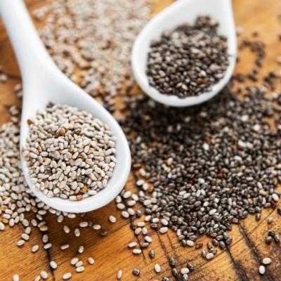 White and black chia seeds on white spoons