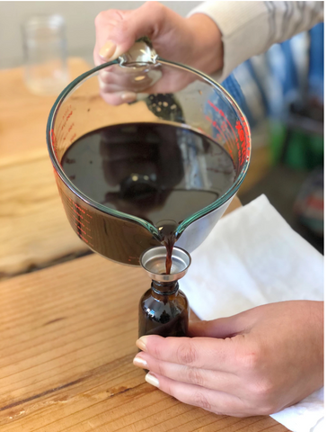 pouring elderberry elixir into medicine bottle