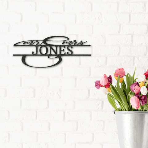 Metal sign of custom last name and in cursive the letter mr and mrs hanging on the wall next to a vase of tulips