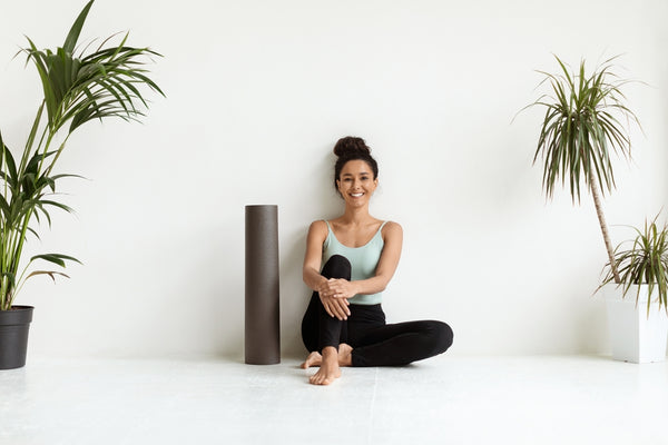 A woman in activewear sitting next to her yoga mat