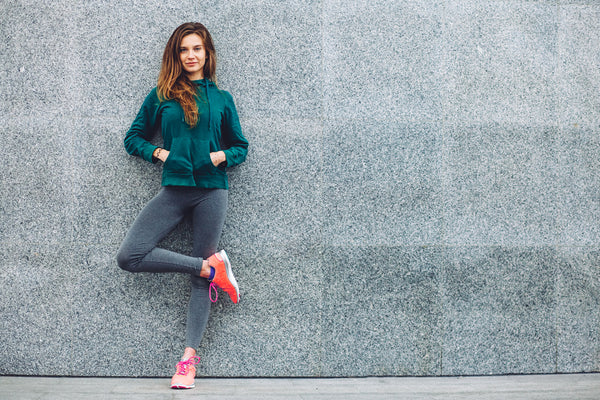 Women in sportswear standing with hands in her hoodie 