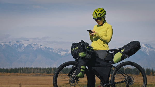 A woman in sportswear using mobile next to her bicycle