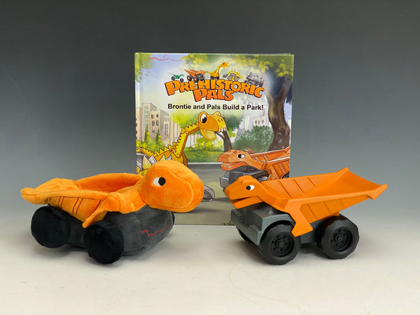 Bianca plush toy and plastic toy in front of prehistoric pals book, Brontie and pals build a park.  The plush and plastic toy are orange iguanodon landmover toys.
